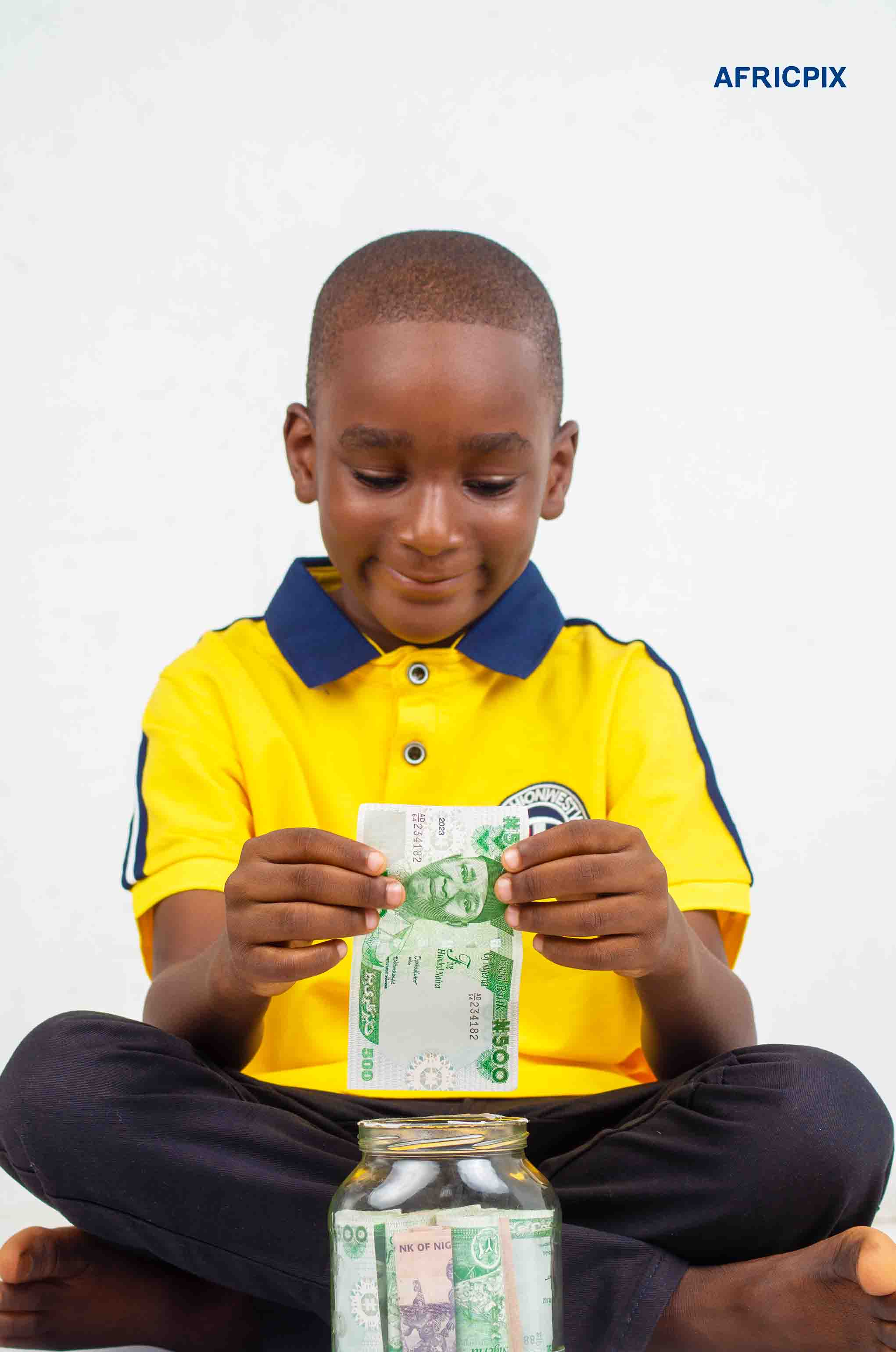 Nigeria Boy Child Sitting Down Holding Naira In Jar